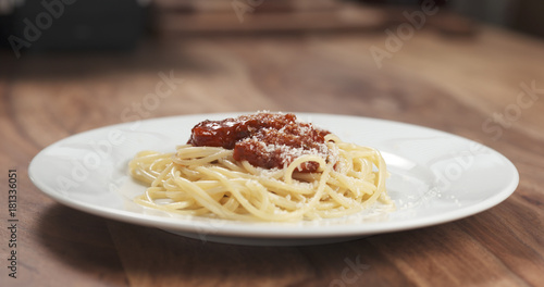 classic spaghetti bolognese with parmesan on plate on table