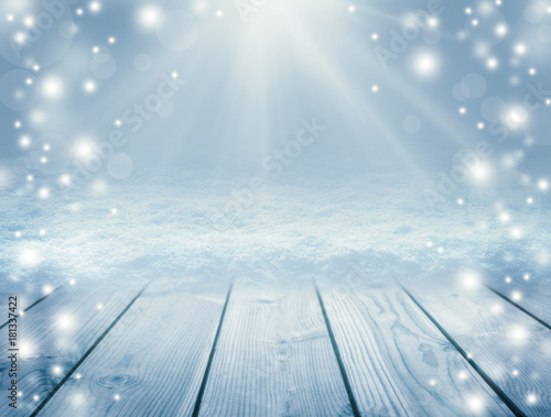Blue wooden background and winter. Empty table and blizzard. Christmas background. Sun rays and snow. New Year background.