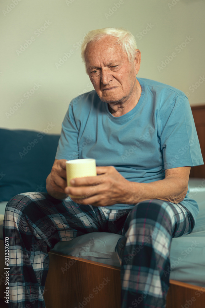 Senior Man Sitting On Bed At Home Suffering From Depression Senior Man Sitting On Bed At Home Suffering From Depression