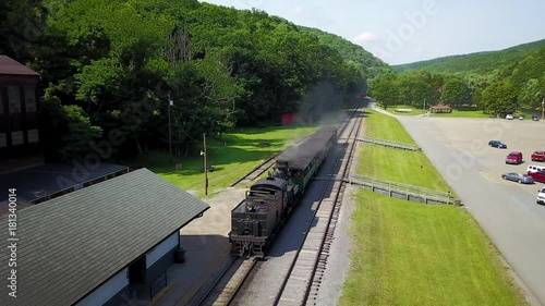 Aerial camera follows a Cass Scenic Railroad train pulls several tourist cars backwards as it moves toward the station with passengers loaded. photo