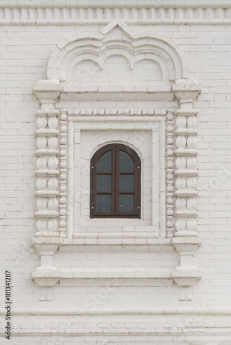 Arched window with wooden frame in a white brick wall © watman
