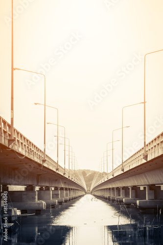 view under the grey  concrete bridge in the city with water under and filter effect construction concept