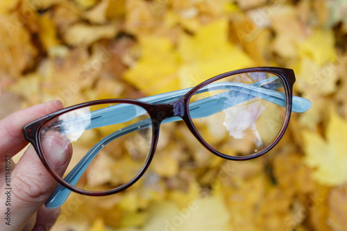 Glasses on the background of autumn yellow leaves. hand holding glasses 