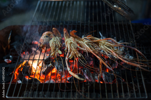 Grilled prawns on grille with fire in market are cooked with a charcoal stove Like making barbecue, To bring the sale for customers.