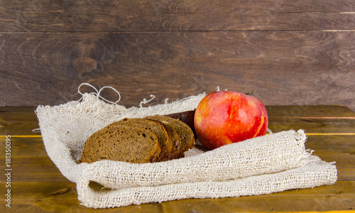 a few pieces of bread and an apple on a burlap on a wooden surface