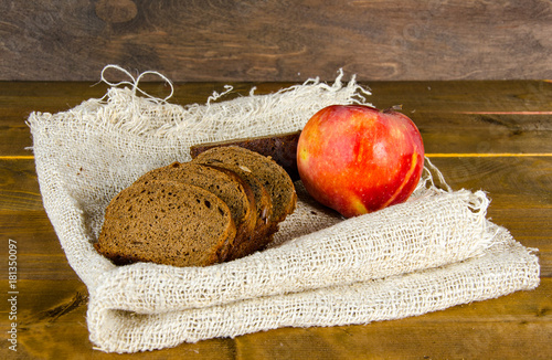 a few pieces of bread and an apple on a burlap on a wooden surface