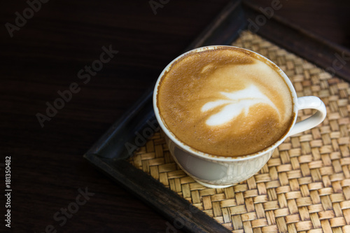 A cup of Latte art coffee on wooden plate