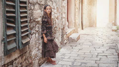 Cute young girl walking in the old town. Nice female child in medieval city.