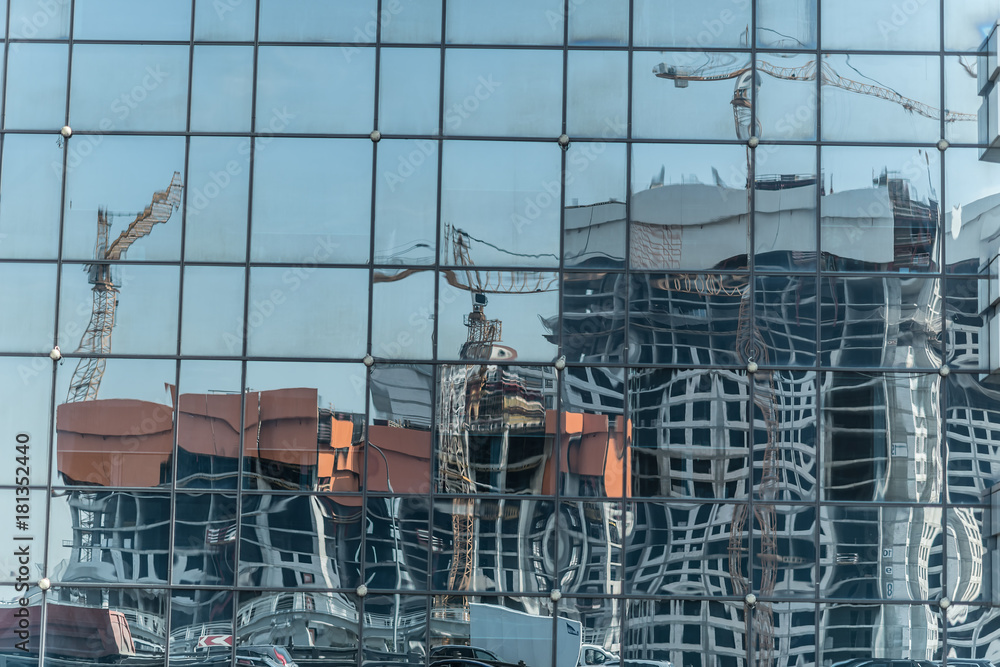 Reflection of tower cranes building construction on building mirror. Abstract background.