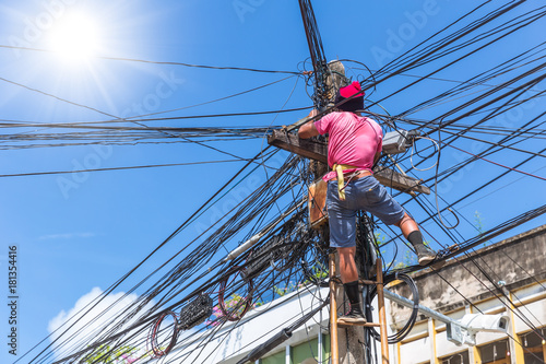 no safety worker technician installing Internet cables on the electricity poles in asian country