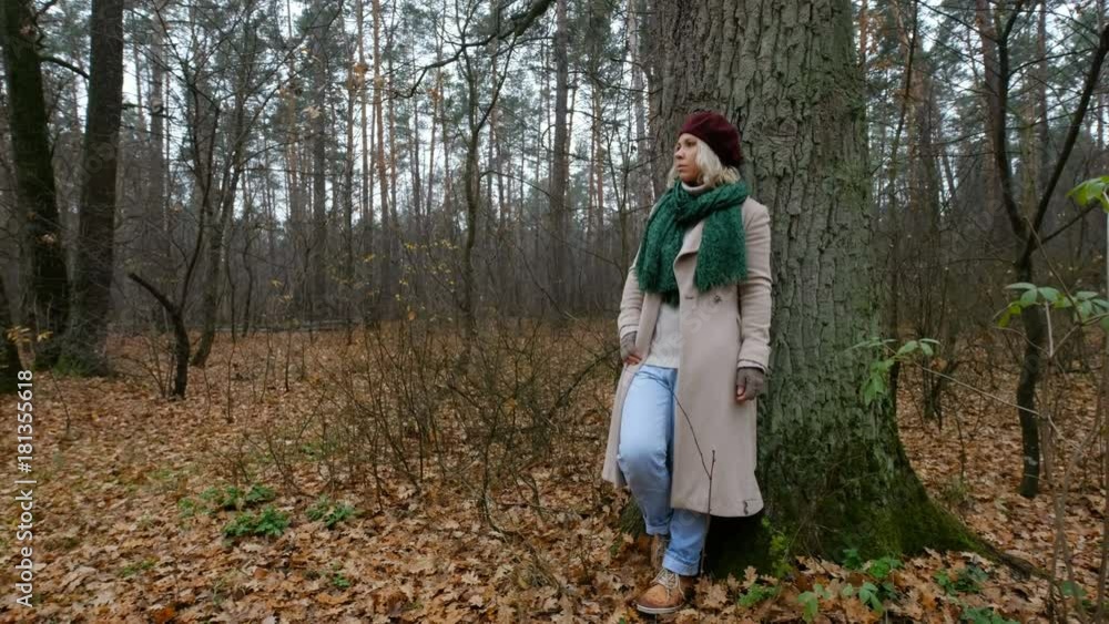 woman in a beige coat walking in an autumn park woman in a beige coat walking in an autumn park