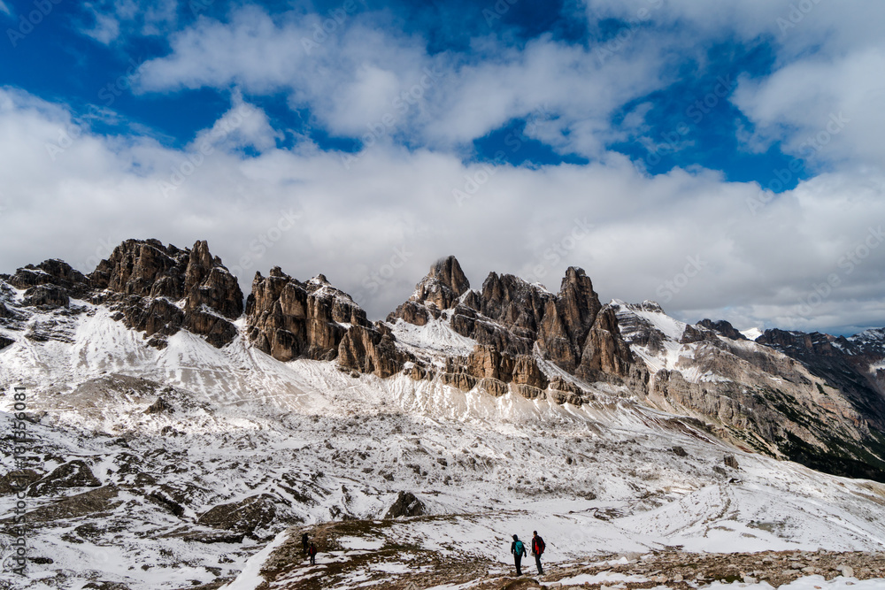 hikers on a trail in the backcountry of the Dolomites in Italy near Corvara after a fresh snowfall in autumn