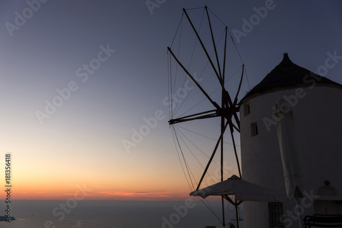 Famous attraction of Oia village at sunset with windmill in Santorini Island. Aegean Sea
