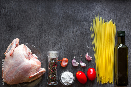 Pasta ingredients. Chicken breasts, Cherry tomatoes, spaghetti pasta, oil, spices and garlic on the wooden table. Space for text. photo