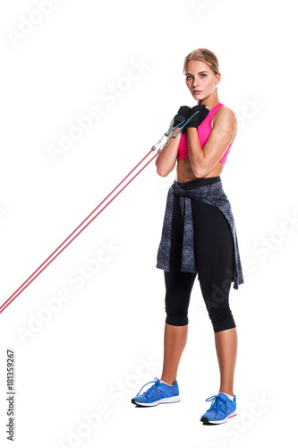 Strong woman using a resistance band in her exercise routine. Young woman performs fitness exercises on white background. photo