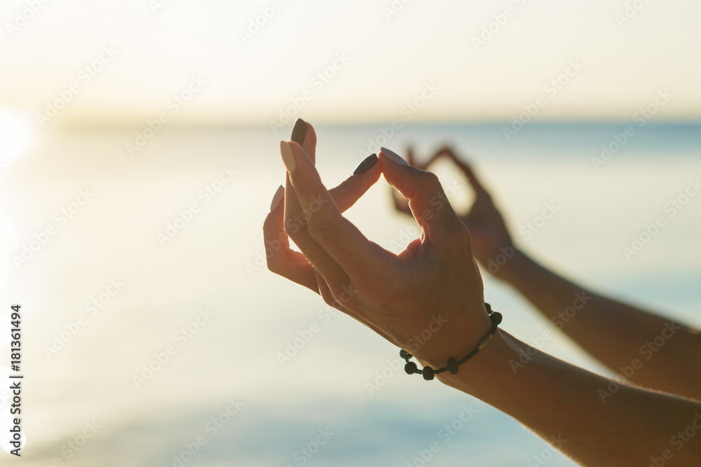Close up woman meditating in the lotus position at sunset