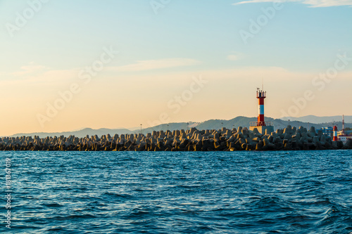 View of the lighthouse on the northern mole of Sochi from the sea at sunset, Russia 
