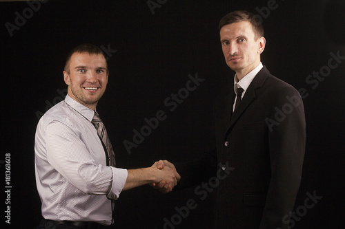 two business partners on a black background shaking hands