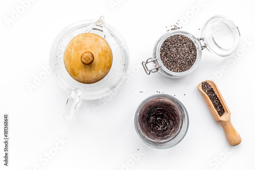 Brew chia seeds. Jar with seeds, scoop, bowl, tea pot with hot water. White background top view copyspace