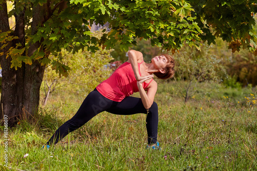 Yoga in the open air. Happy woman doing yoga exercises, meditate in the park. Yoga meditation in nature. 