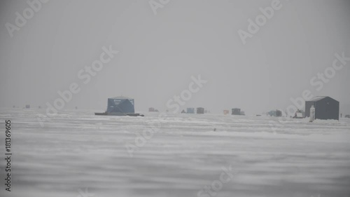 A shot of the ice huts on the ice and people working