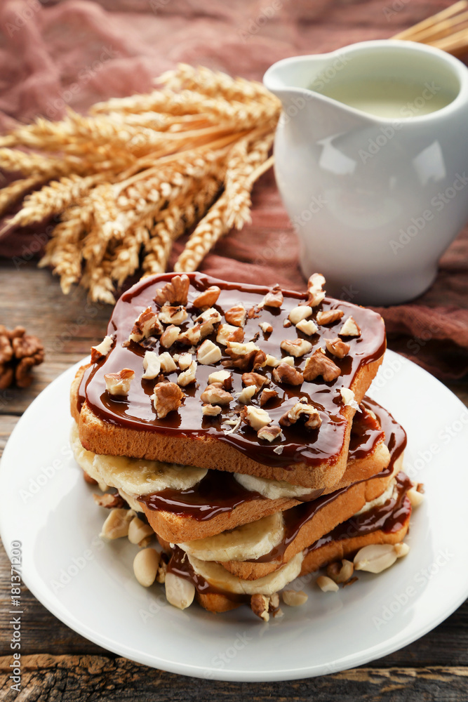 Toasts bread with bananas, walnuts and chocolate on grey wooden table