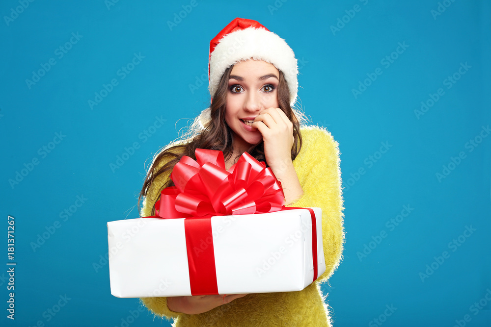 Beautiful young girl holding gift box on blue background Beautiful young girl holding gift box on blue background