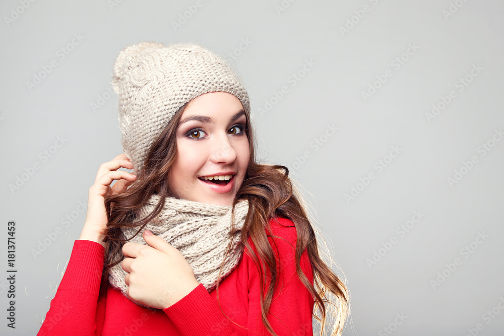 Beautiful young girl in hat and scarf on grey background