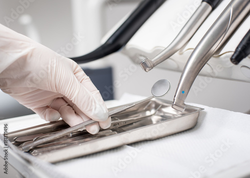Quadro su tela Dentist with gloved hand is picking dental mirror in dental office