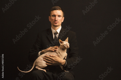 Foto A man in a classic suit on a black background with a cat on his knees