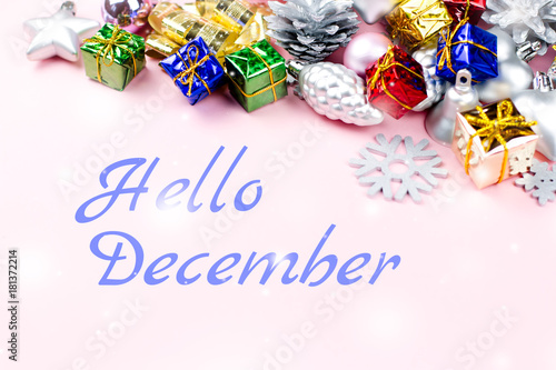 Hello December greeting card with colorful Christmas ornaments, presents in the background