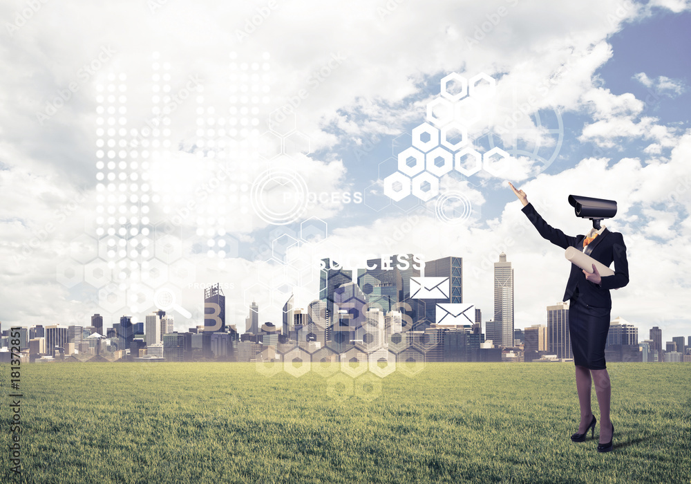 Camera headed woman standing on green grass against modern citys