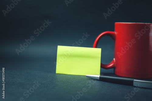 Coffee mug with sticky note and pen.