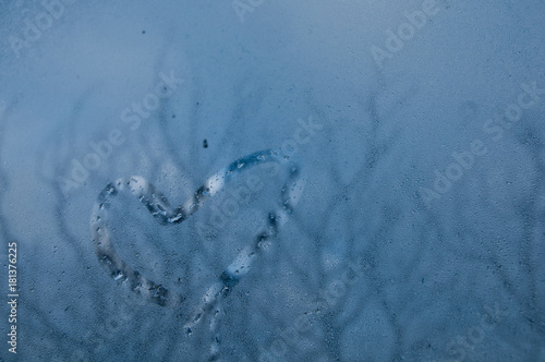 Heart shape on droplet window of cold misty morning