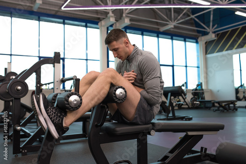 Full length side view of muscular man doing crunches on stand while working out in modern gym