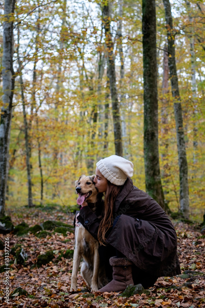 happy little girl with a dog in a beech forest. Autumn season