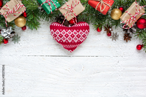 Christmas background with fir branches, knitted heart, decorations, gift boxes and pine cones