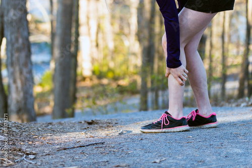 Sports injury leg cramp on running trail.