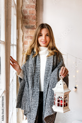 Fotografie Girl in warm knitted bedcover with candle lantern, red christmas decorations in
