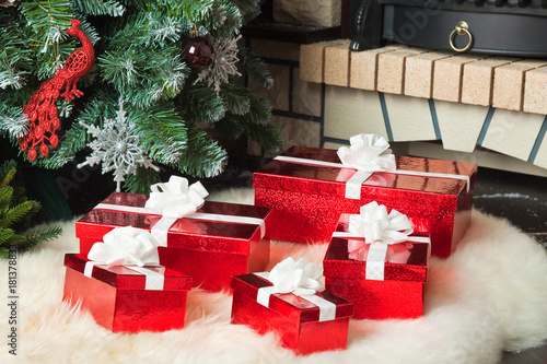 Red gift boxes near christmas tree and fireplace
