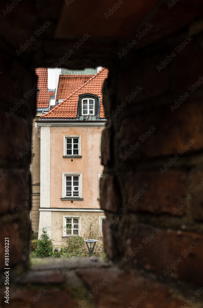 Windows in facade of old building framed by hole in brick wall cloudy day, Warsaw Poland