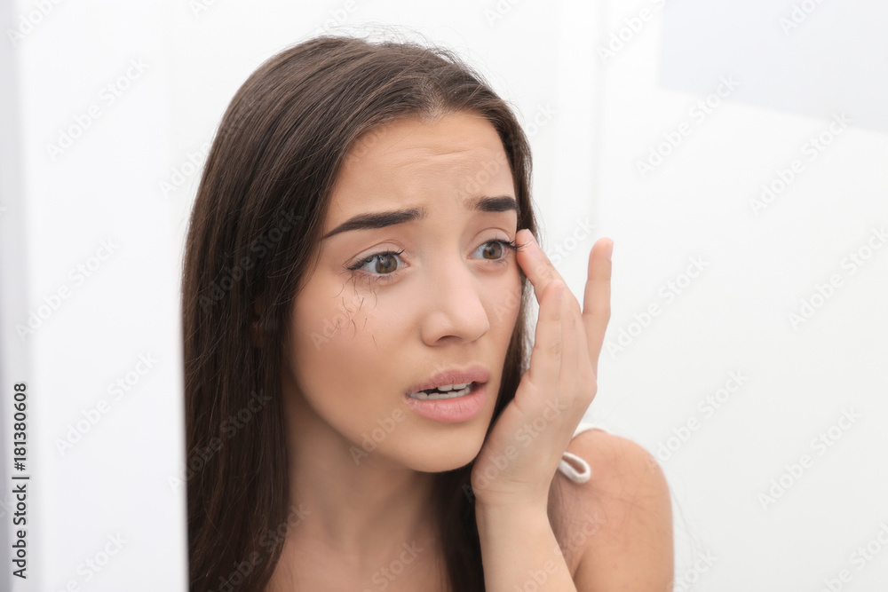 Young woman with eyelash loss problem on light background Young woman with eyelash loss problem on light background