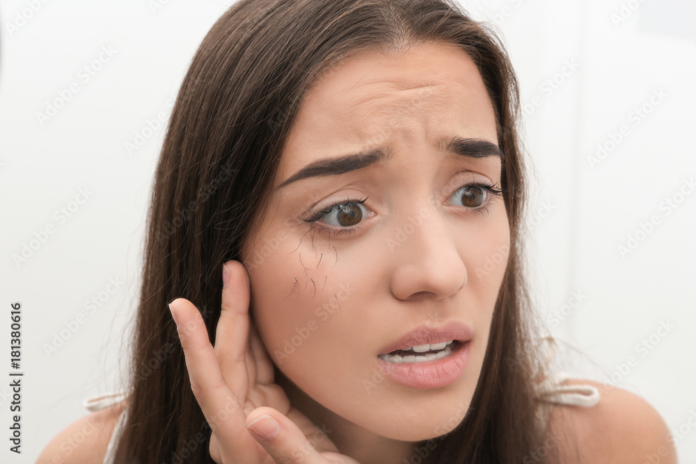 Young woman with eyelash loss problem on light background Young woman with eyelash loss problem on light background