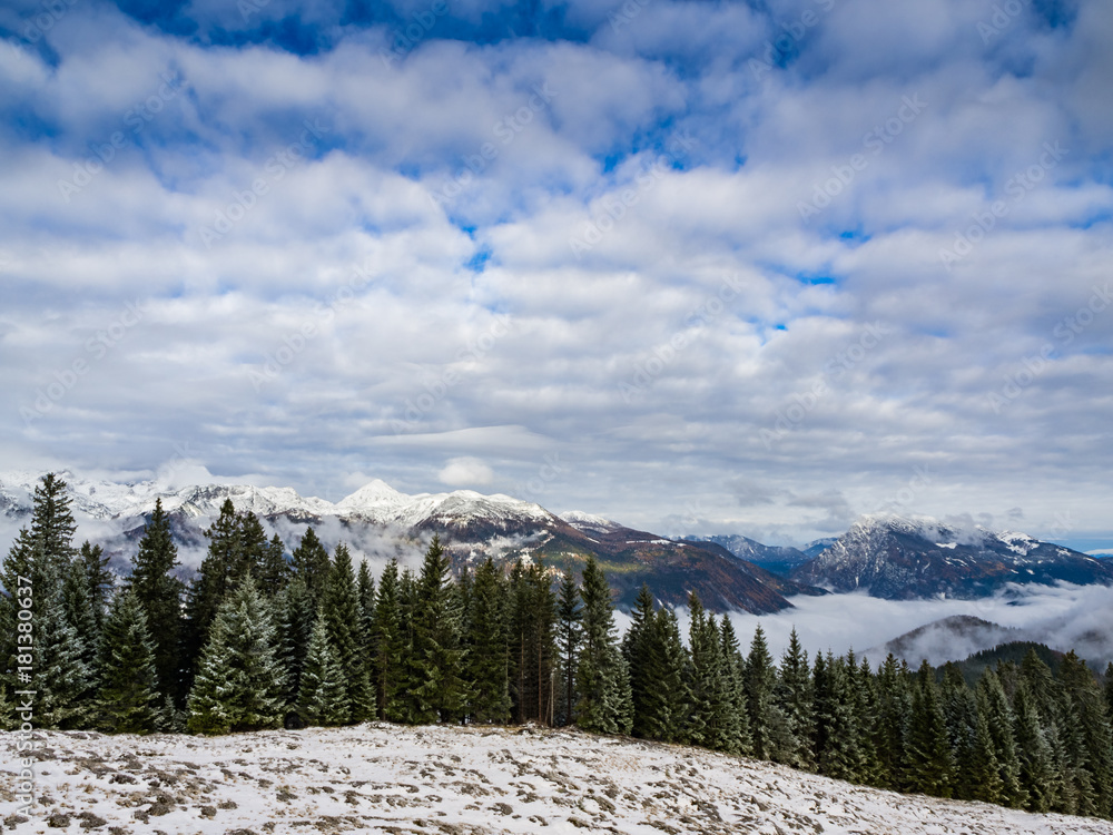 Snowy peak of Ojstrica mountain rising above the spruce forest on Kranjska reber mountain in Kamnik-Savinja mountain range
