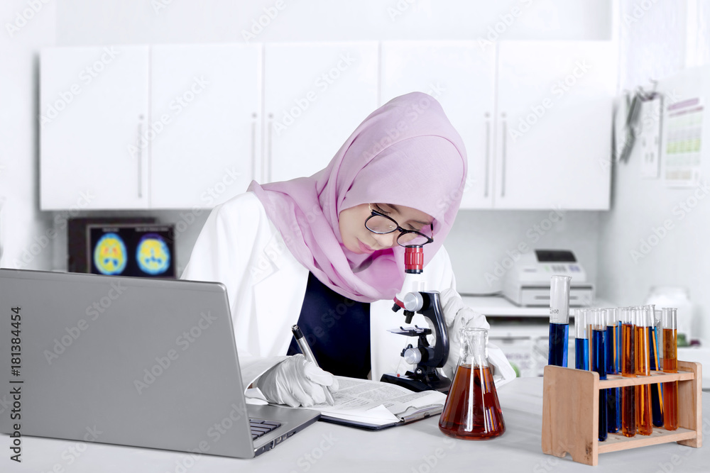 Muslim researcher working with microscope Muslim researcher working with microscope