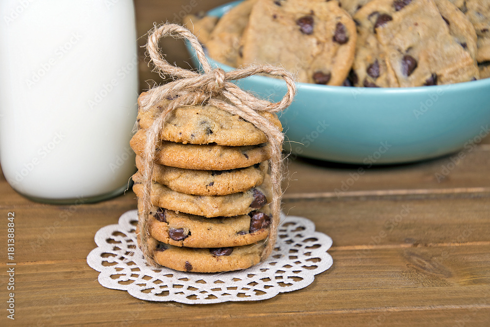 chocolate chip cookies with string bow and white milk on rustic wood