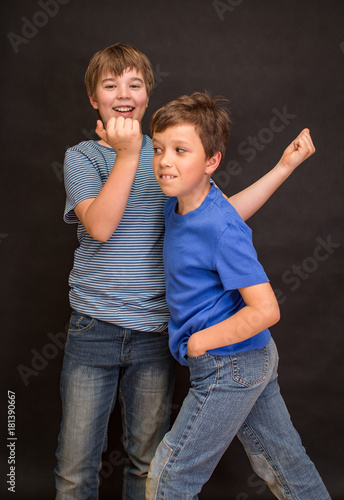 Brothers having fun whilst posing. Boys portrait, young little cute and adorable kids, little obstreperous scamps. Poses, face expressions, ease,  black background. photo