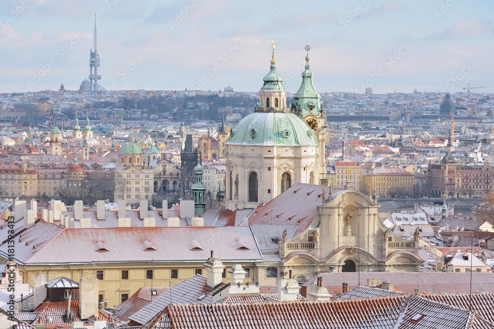 Fototapeta premium Winter Prague panorama with St. Nicholas church, roofs of Lesser Town, Old Town and TV Tower