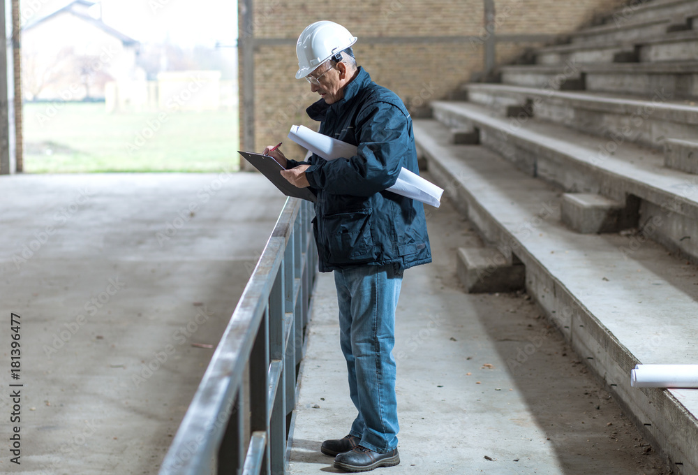 Senior construction manager controlling building site with plan. Senior construction manager controlling building site with plan.
