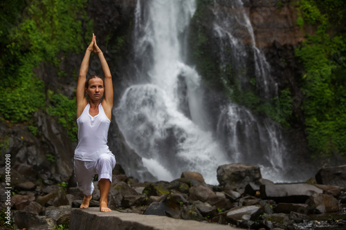 Woman practices yoga at Gitgit waterfall on Bali in indonesia